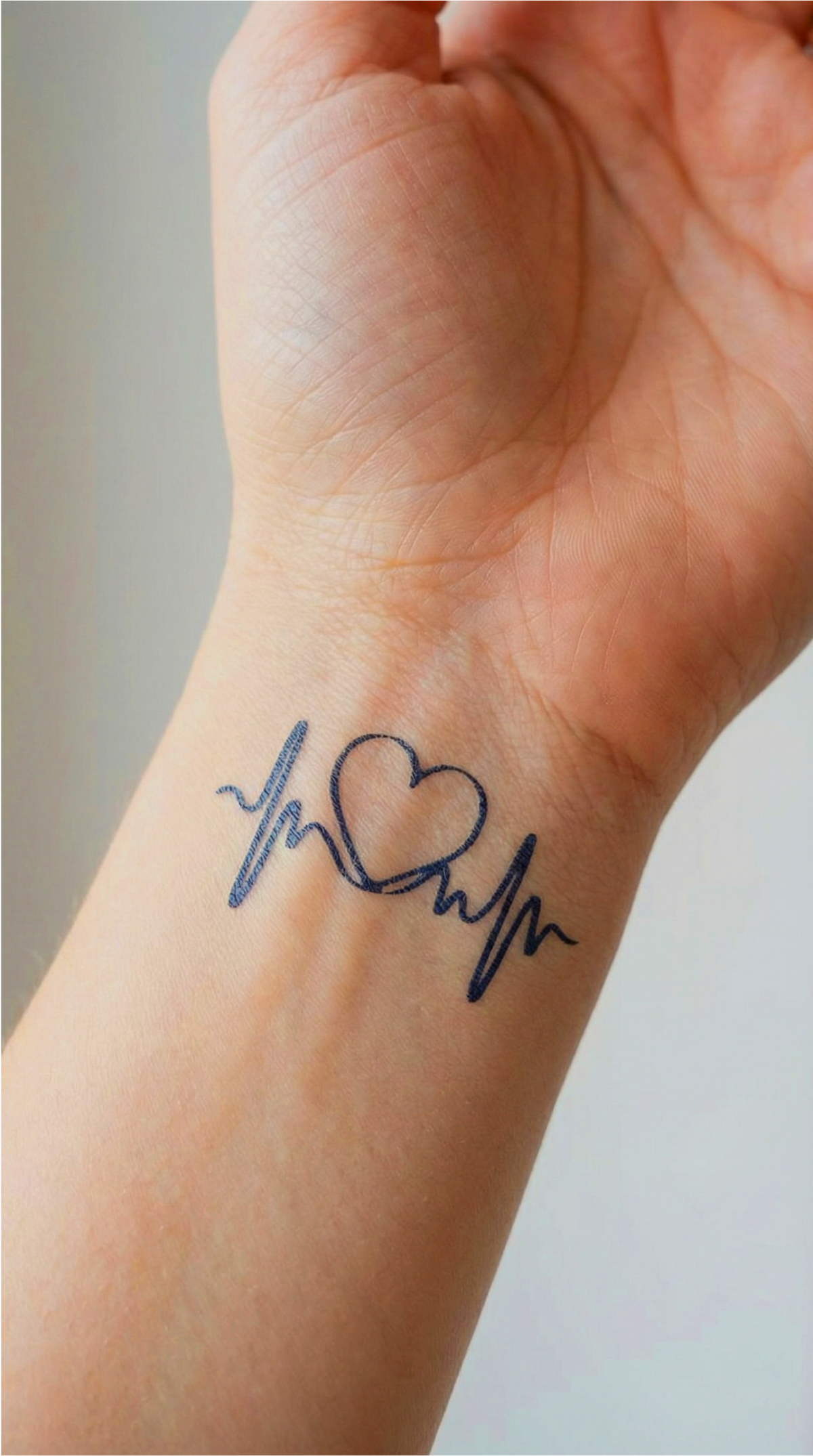 Tatuajul semipermanent Heartbeat, cu inimă și linie de puls, aplicat pe antebraț urmând axa lungă a brațului